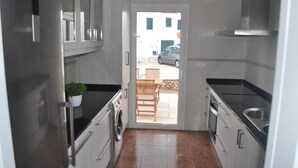 Une cuisine compacte équipée d’un lave-linge, d’un évier et offrant une vue sur l’extérieur.