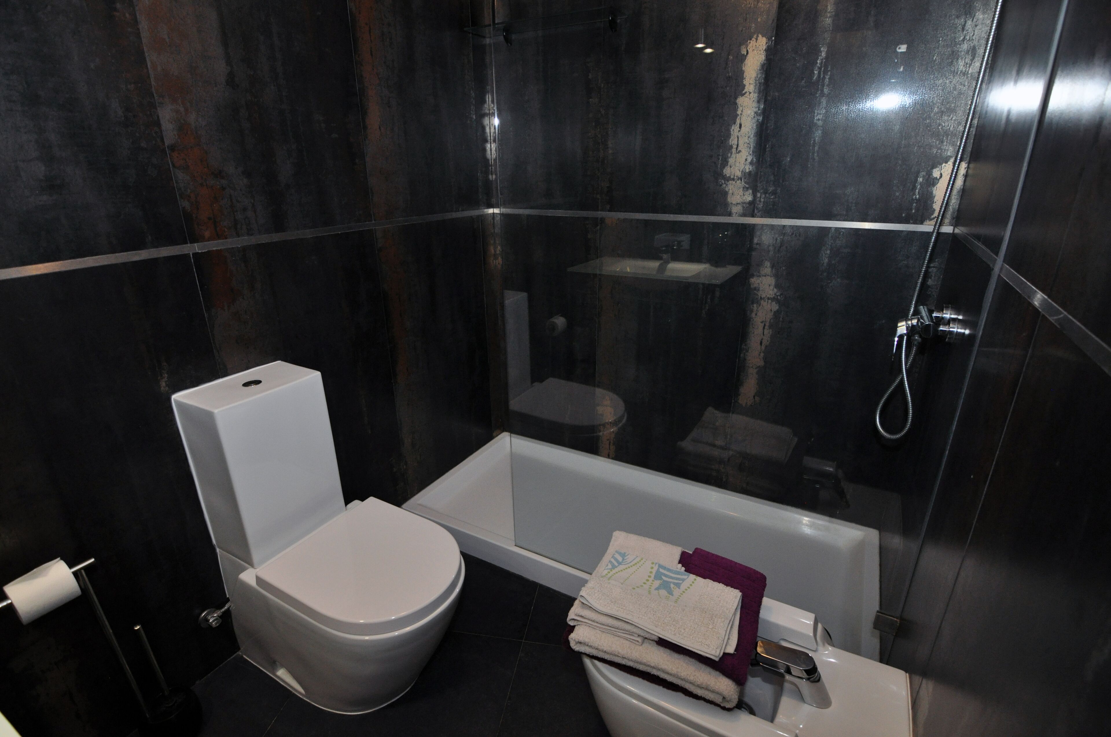 A modern bathroom with a toilet, a bathtub, and a shower.