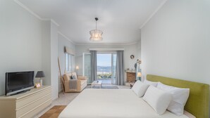 Habitación de hotel con una cama grande, televisión, sofá y vistas al exterior.