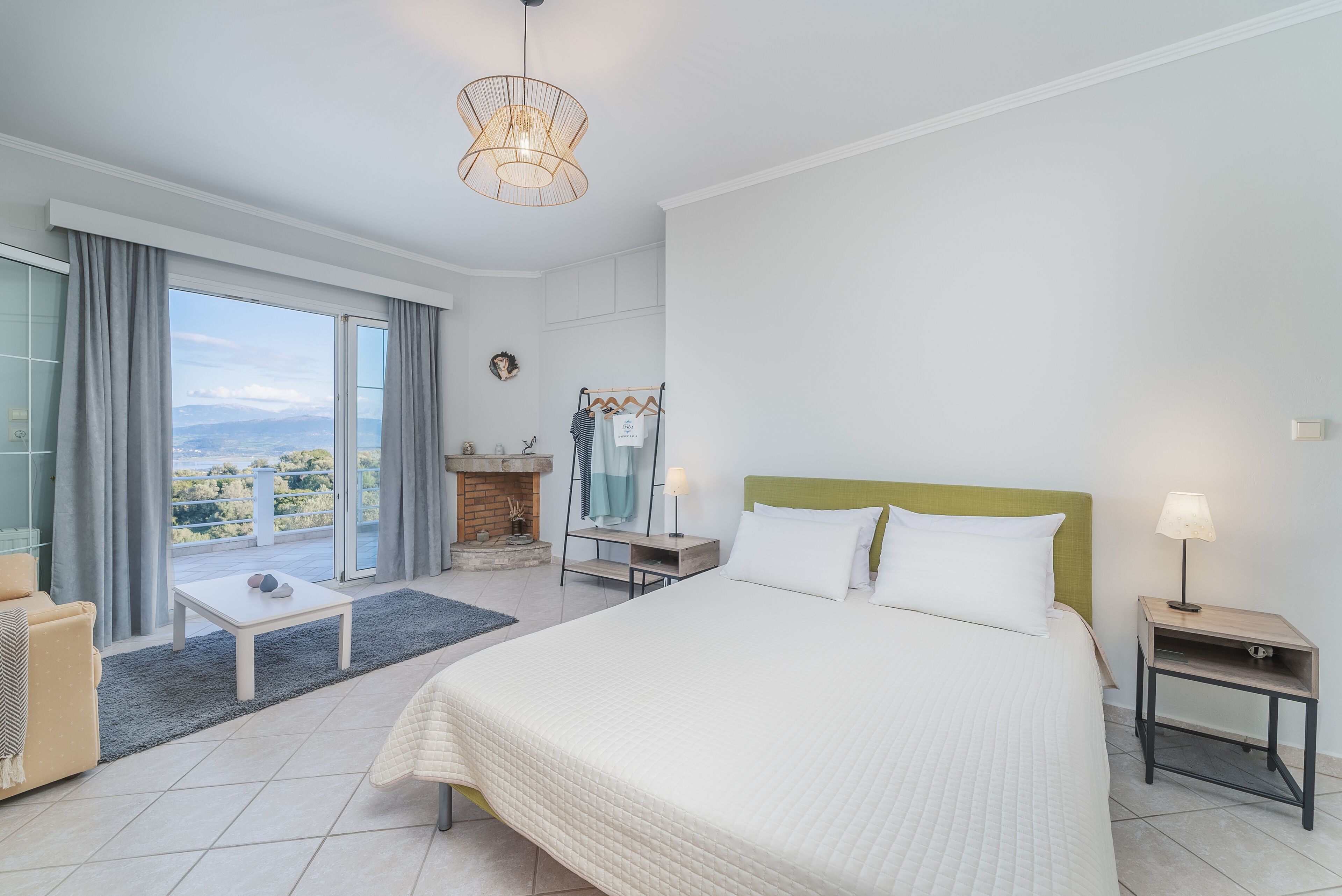 A modern hotel room with a large bed, a small table, a nightstand, and a view of the outdoors.