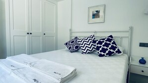 A neatly made bed with white linens and patterned pillows, a white wardrobe, and a small bedside table with a vase. - Kalkan Duplex Apartment - prime location with stunning views (Kalkan)