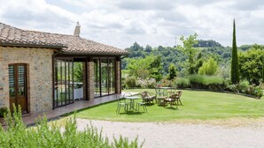 A stone building with a tiled roof, a covered patio with outdoor seating, and a well-maintained lawn. - Two-bedroom apartment with private entrance (Città della Pieve)
