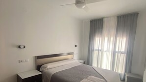 Une chambre à coucher avec un lit, une table de chevet et un ventilateur de plafond.