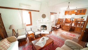 Un salon chaleureux avec une cheminée, des meubles en bois et une cuisine en arrière-plan.