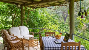 Un espace extérieur abrité, aménagé avec des meubles en osier et une nappe à carreaux.