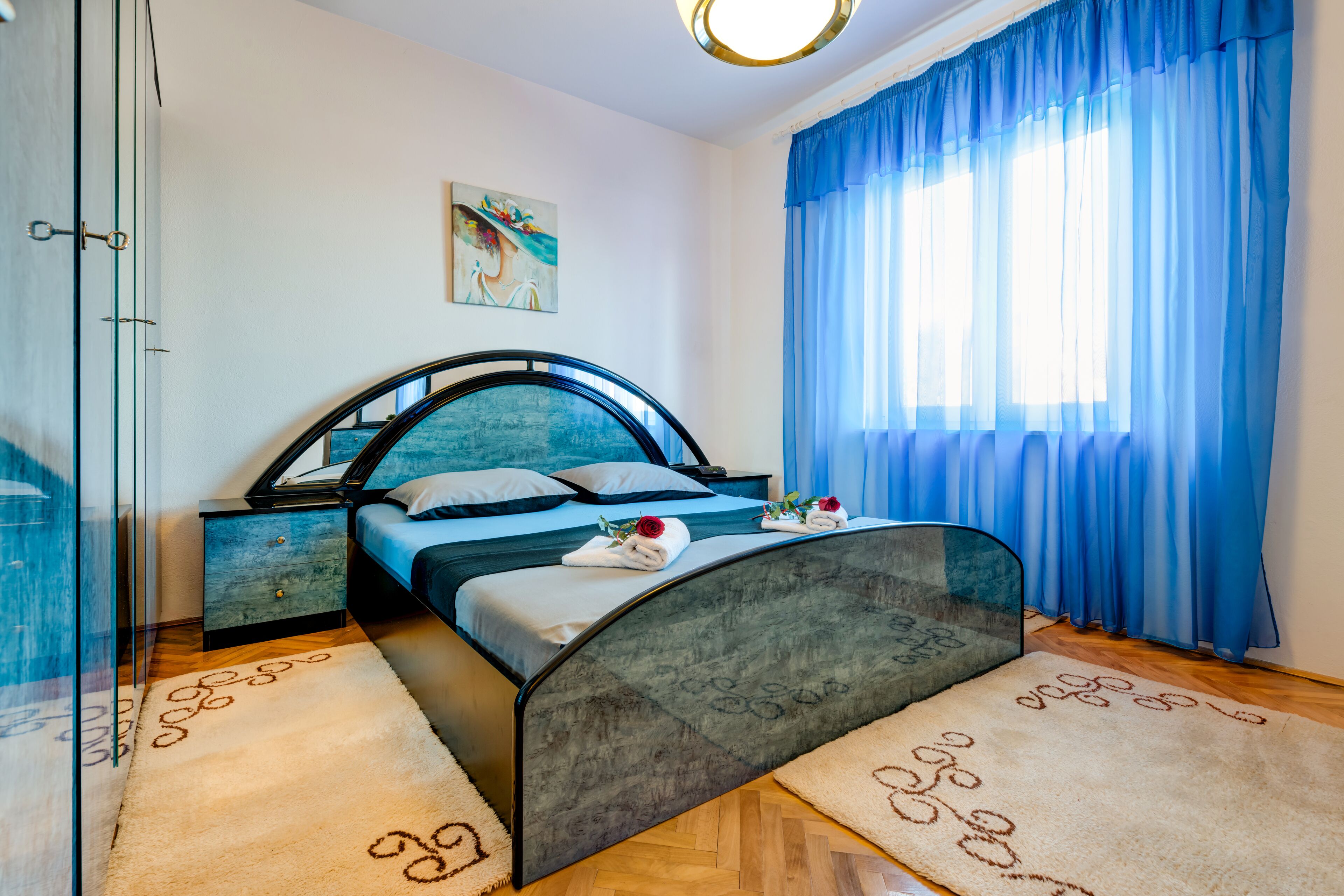 Une chambre moderne avec un lit aux lignes courbes, une douche en verre et une grande fenêtre ornée de rideaux bleus.