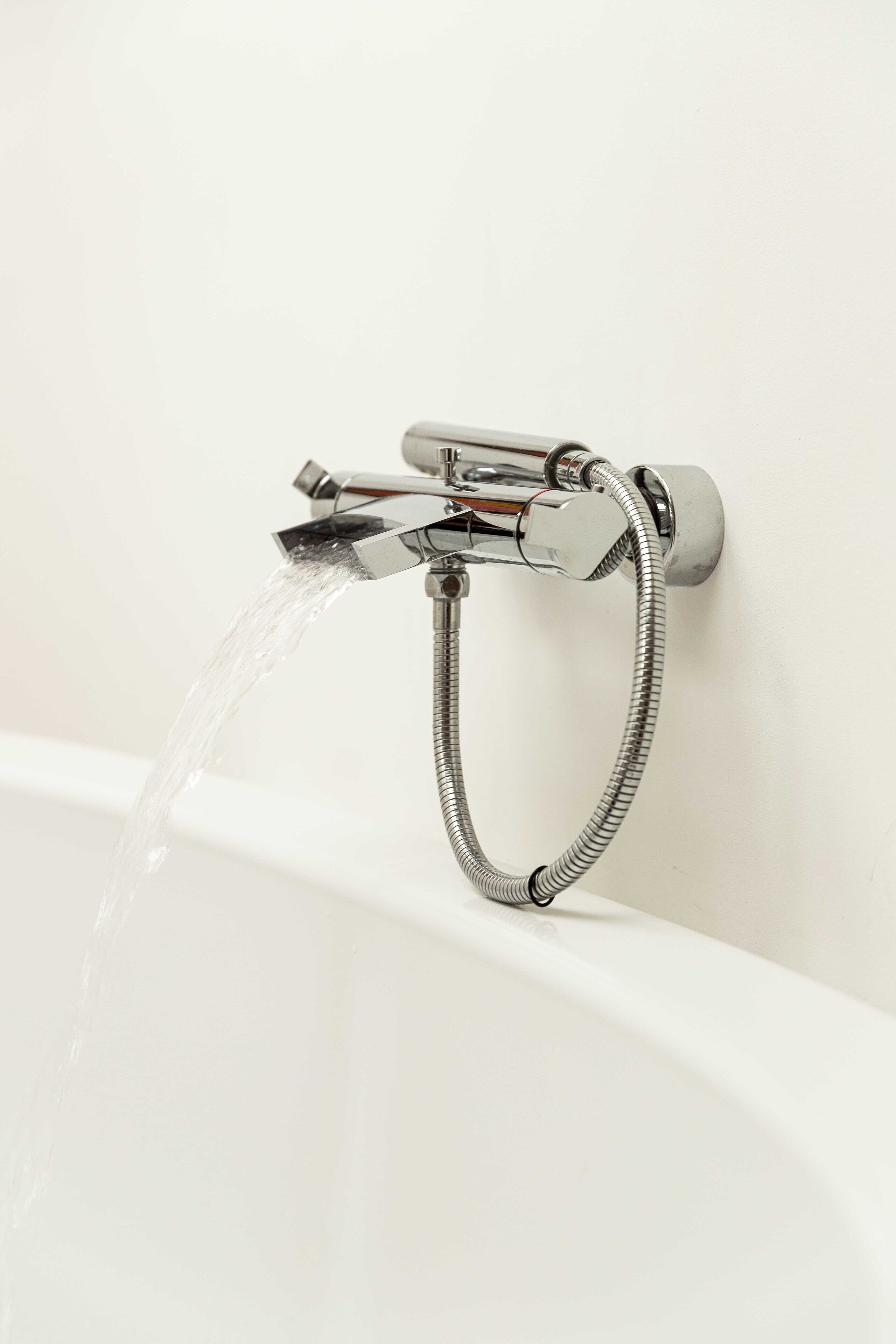 A modern bathroom with a chrome faucet and shower hose.