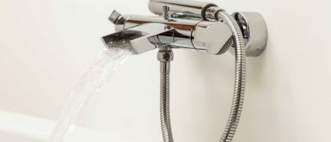 A modern bathroom with a chrome faucet and shower hose.