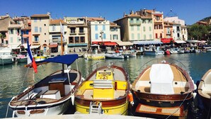 A marina with boats docked, a clear blue sky, and colorful buildings in the background.