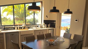 A modern kitchen with a large dining table, chairs, and pendant lights.