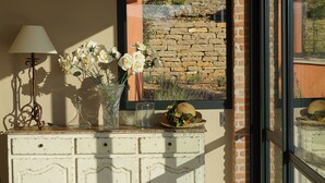 A white dresser with a vase of white flowers, a lamp, and a glass container.