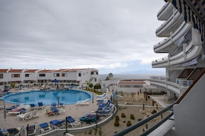 A hotel with a pool area, lounge chairs, and a view of the sea. - Club Atlantis 28 - One Bed with air conditioning (Adeje)