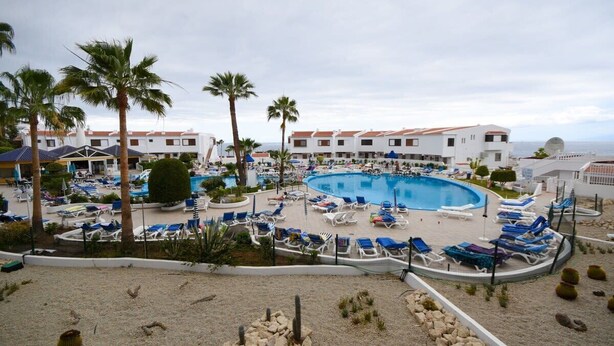 A resort with a large pool surrounded by lounge chairs and palm trees.