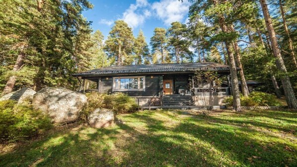 Une cabane entourée d’arbres, sous un ciel dégagé.
