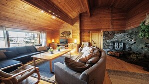 A cozy cabin interior with a stone fireplace, wooden walls, and a comfortable seating area. - Skitunäs Seaside villa in Pyhtää (Pyhtää)