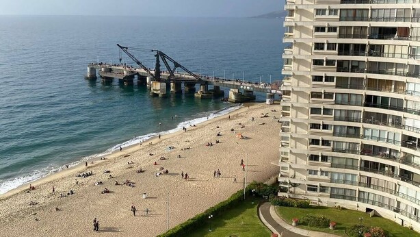 A coastal hotel with a beach, a pier, and a landscaped garden.