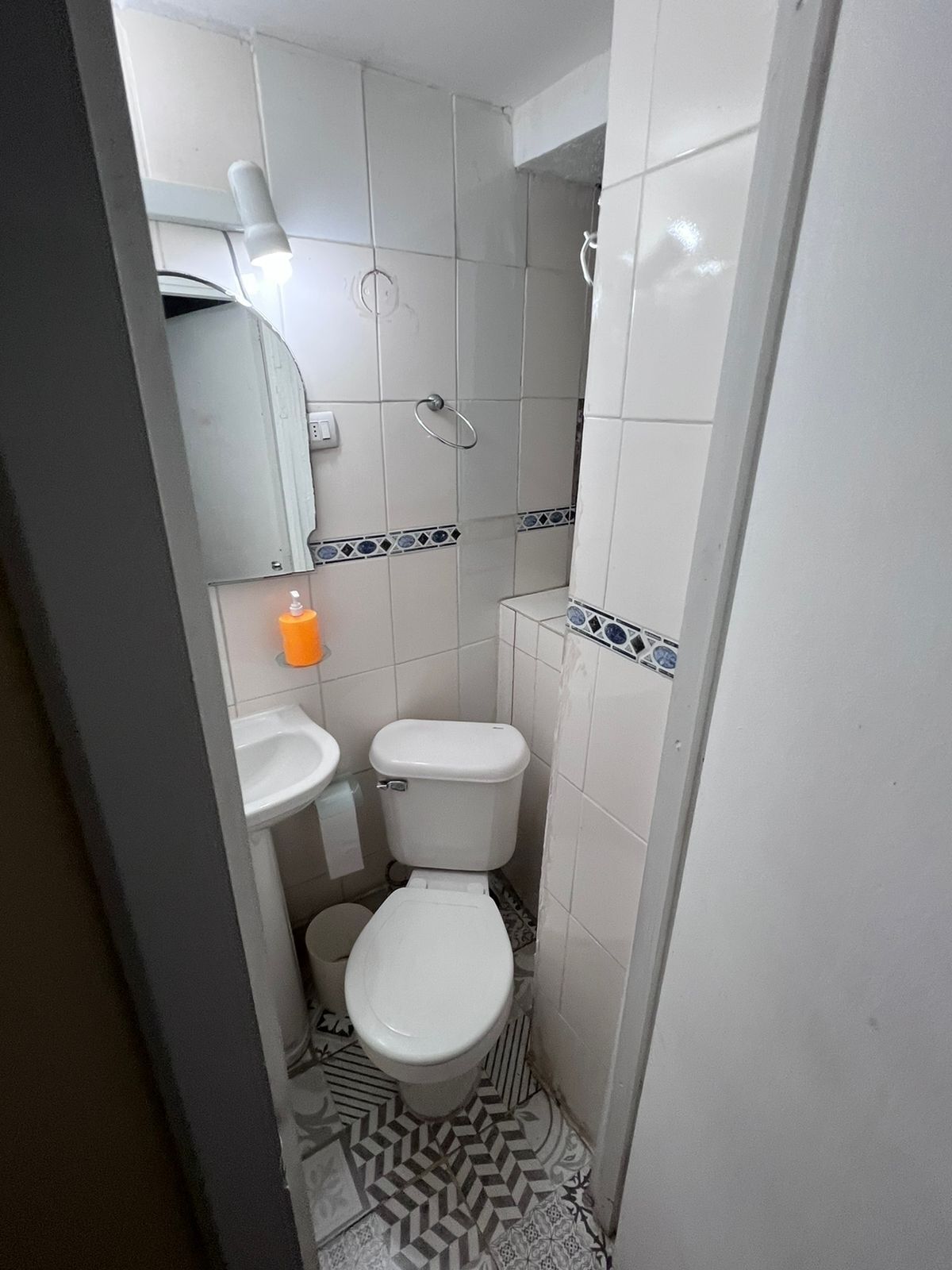 Un bagno piccolo e compatto con il water, il lavandino e uno specchio.
