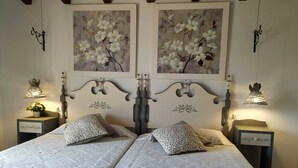 A double bed with a white bedspread and two matching pillows, flanked by nightstands with lamps and decorative items. - Beautiful villa in the middle of nature, 5 minutes away from the best beaches of Mallorca. (Muro)