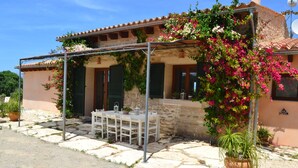 A stone building with a covered patio, outdoor seating, and potted plants. - Beautiful villa in the middle of nature, 5 minutes away from the best beaches of Mallorca. (Muro)
