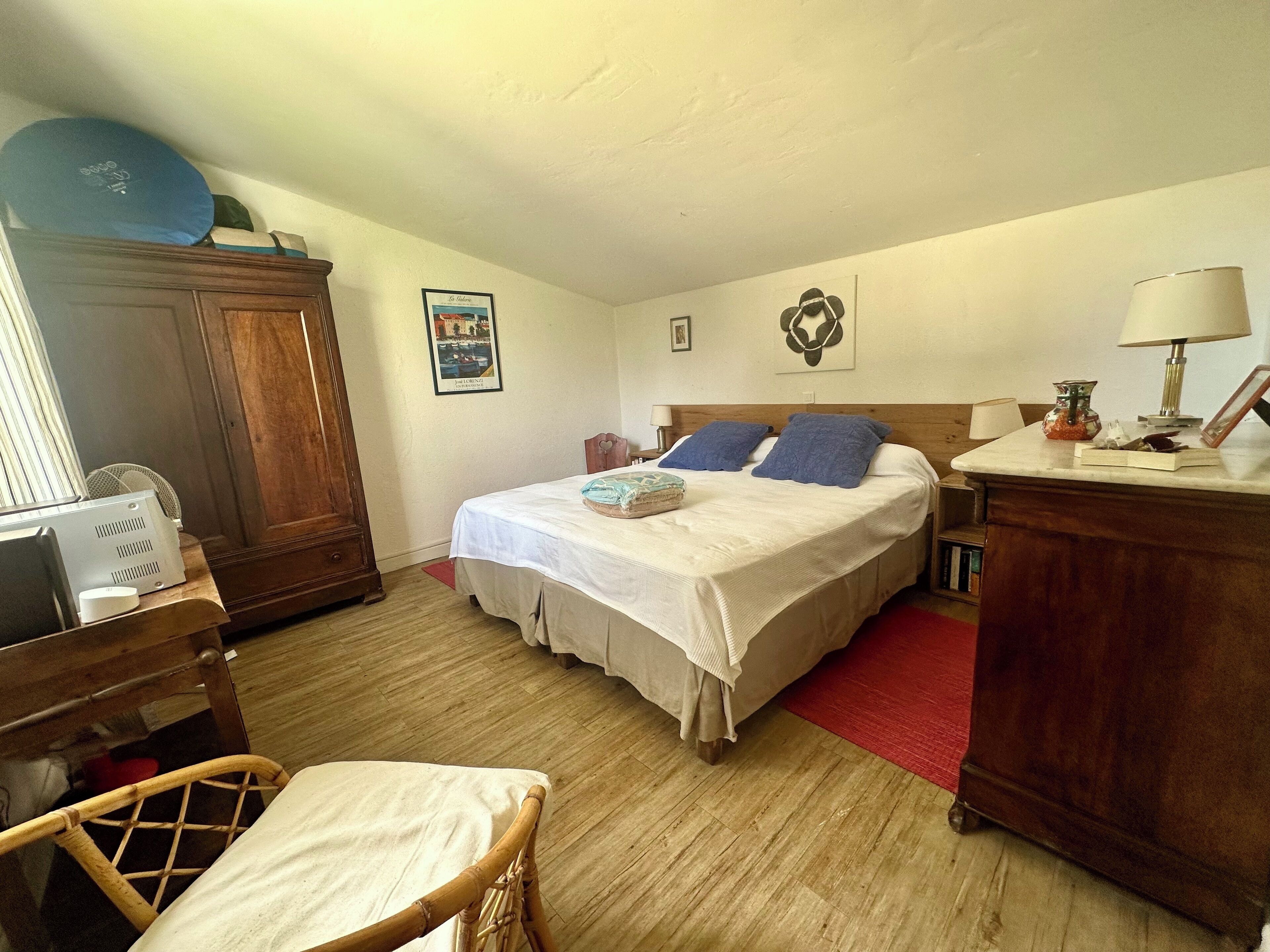 Quarto com cama, móveis de madeira, escrivaninha e cadeira.
