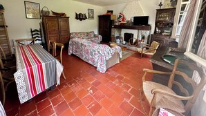 A cozy living room with a fireplace, a dining area with a striped tablecloth, and a kitchen area with wooden cabinets. - Golfe Ajaccio sud La Castagna: Charming waterfront home! (Coti-Chiavari)