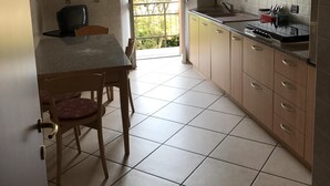 A kitchen with wooden cabinets, a tiled floor, and a dining area with a table and chairs. - Just 4 km from Arona, in Meina Villa, surrounded by greenery with views of Lake Maggiore and Rocca Angela. (Pisano)