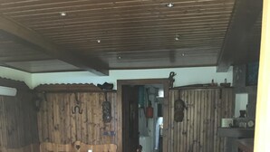 A rustic wooden interior with a brick floor, wooden tables and benches, and a visible doorway leading to another room. - Just 4 km from Arona, in Meina Villa, surrounded by greenery with views of Lake Maggiore and Rocca Angela. (Pisano)