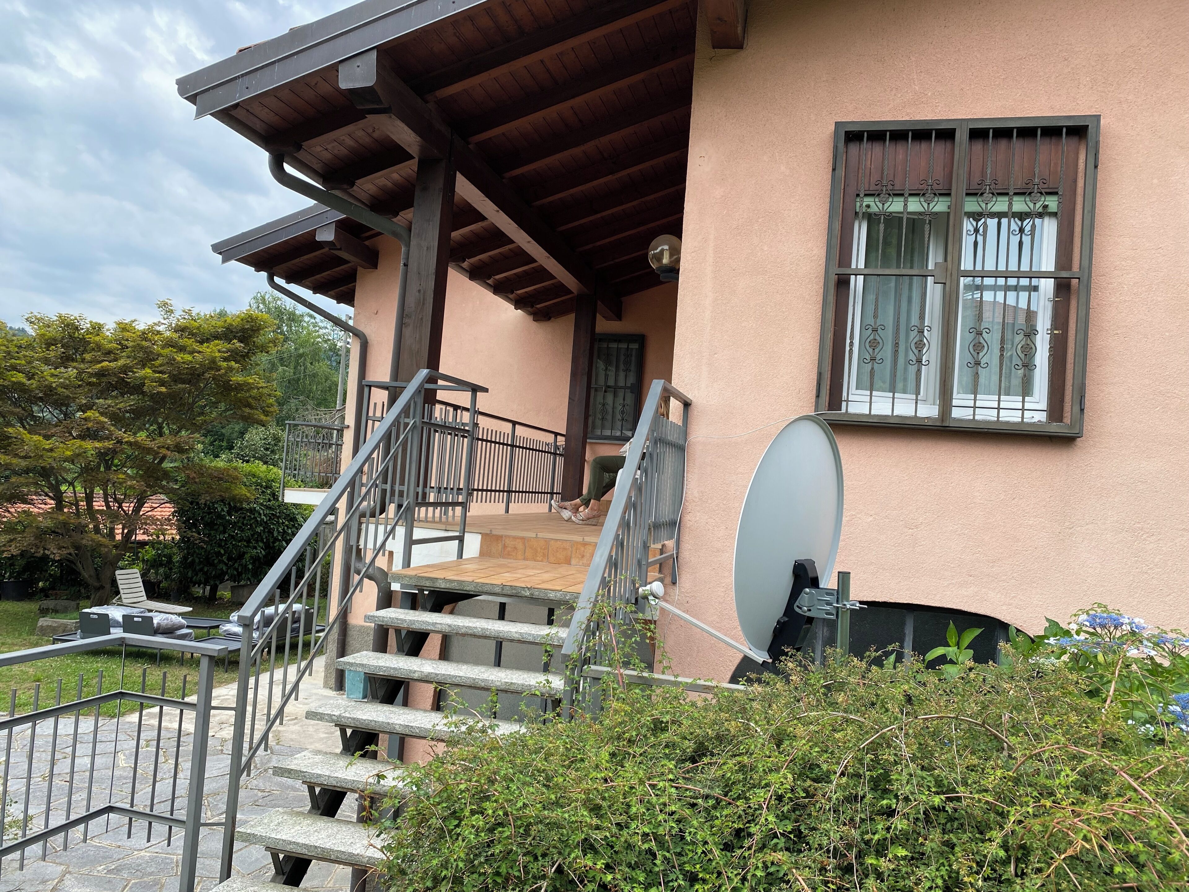 Un bâtiment doté d’un porche, d’un espace extérieur aménagé pour s’asseoir et d’une antenne parabolique.