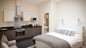 A modern hotel room with a kitchenette, a bed with striped pillows, and a skylight. - Toothbrush Apartments - Central Ipswich East - Rope Walk (Ipswich)