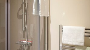 A glass-enclosed shower with a handheld showerhead and a towel rack with towels. - Toothbrush Apartments - Central Ipswich East - Rope Walk (Ipswich)