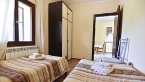 Une chambre avec deux lits, une armoire et une fenêtre.