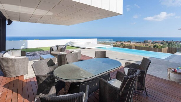 Una terraza en la azotea con piscina, mobiliario exterior y vistas al océano.