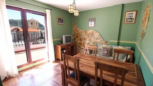 A dining area with a wooden table and chairs, a stone accent wall, and a television on a wooden stand.