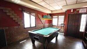 A pool table in a room with brick walls, a window, and a door.