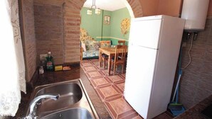 A kitchen with a sink, a refrigerator, and a dining area with chairs and a table.