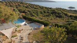 A pool area with a stone deck, surrounded by greenery and mountains in the background.