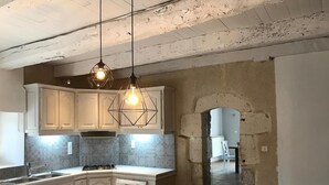 A kitchen with white cabinets, a wooden table, and pendant lights. - Le Petit Paradis - Cottage for 8 people with Private Pool in the Countryside (Caylus)