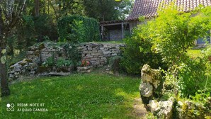 A stone wall, a rustic building with a tiled roof, and lush greenery. - Le Petit Paradis - Cottage for 8 people with Private Pool in the Countryside (Caylus)