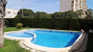 Une piscine rectangulaire à bord incurvé, entourée d’une bordure en pierre et d’une pelouse.