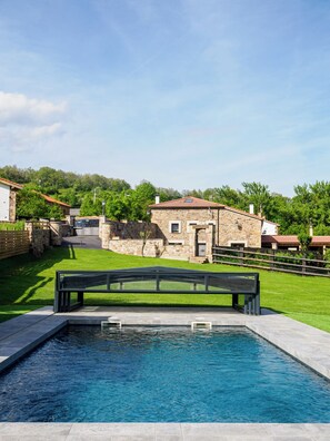 A swimming pool with a stone building in the background. - The House of Pedros (Villar)