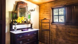 Una habitación con paneles de madera, un tocador, un espejo y una ventana.