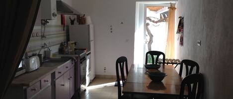A kitchen with a dining table and chairs, a refrigerator, a stove, and a sink.