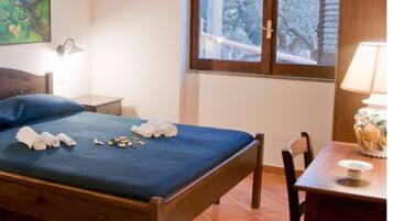 Relax in a cozy retreat with a comfortable bed, a convenient table, and a window offering a peaceful view of the surrounding trees.