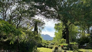 A garden pathway leading to a seating area with a view of mountains.