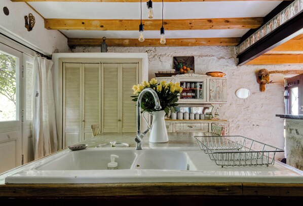 A kitchen with a white sink, wooden beams, a hanging light fixture, and a vase of yellow flowers. - Rustic 18th Century Farmhouse With Pool and view, 20 minutes drive to beaches (Roquebrune-Sur-Argens)