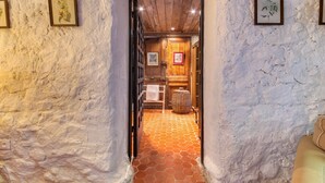 A narrow hallway with white textured walls and a tiled floor leading to a wooden door.