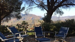A patio with four lounge chairs, a stone floor, and a view of mountains in the background. - Apartment in villa with air-conditioned pool (Castelbuono (Pa))