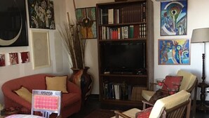 A living room with a sofa, armchairs, a coffee table, a bookshelf, and a television. - Apartment in villa with air-conditioned pool (Castelbuono (Pa))