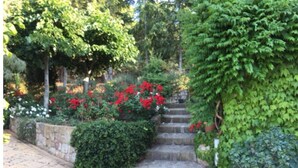 A stone staircase surrounded by lush greenery and red flowers. - Apartment in villa with air-conditioned pool (Castelbuono (Pa))