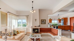 Una sala de estar moderna con chimenea, un sofá, una mesa de comedor y una cocina al fondo.